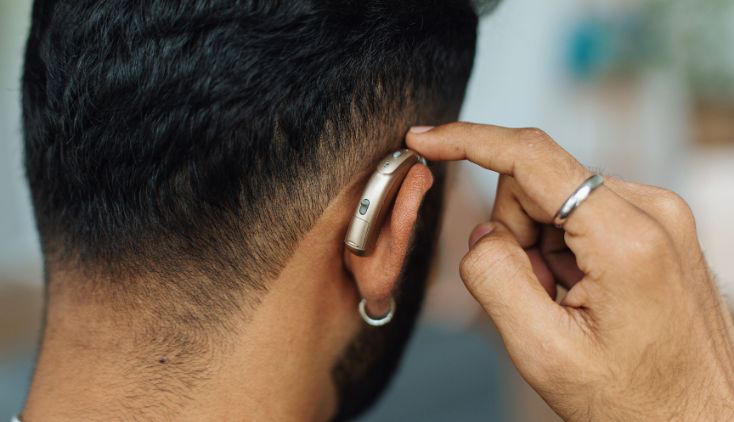 A man touching his hearing aid.